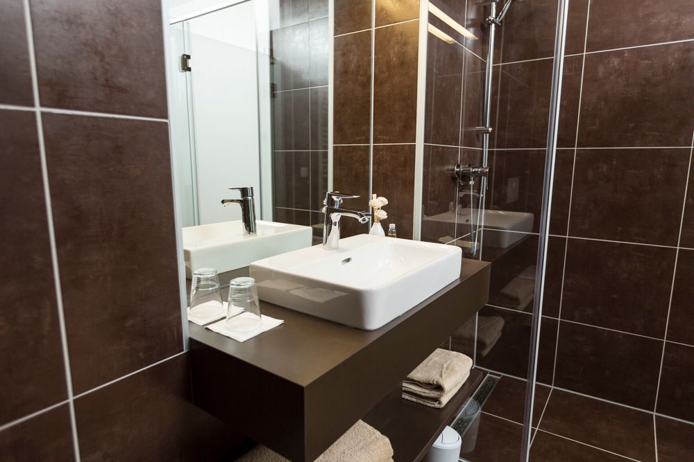 Moderní koupelna s umyvadlem, zrcadlem a sprchovým koutem.