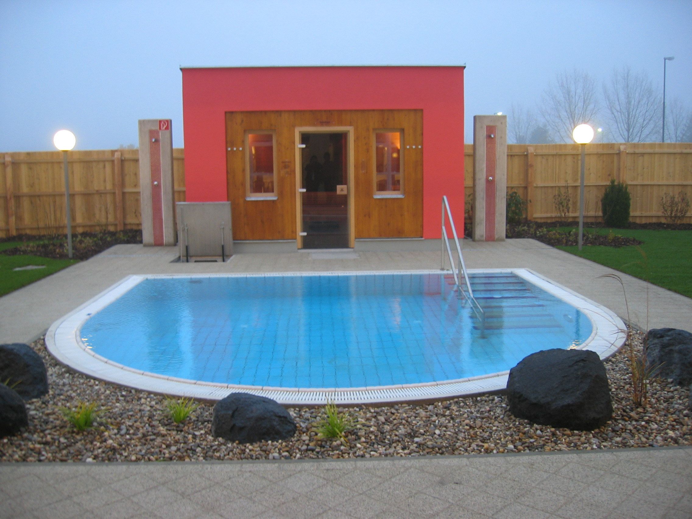 Pohled zvenčí na saunu s malým bazénem a zahradou.