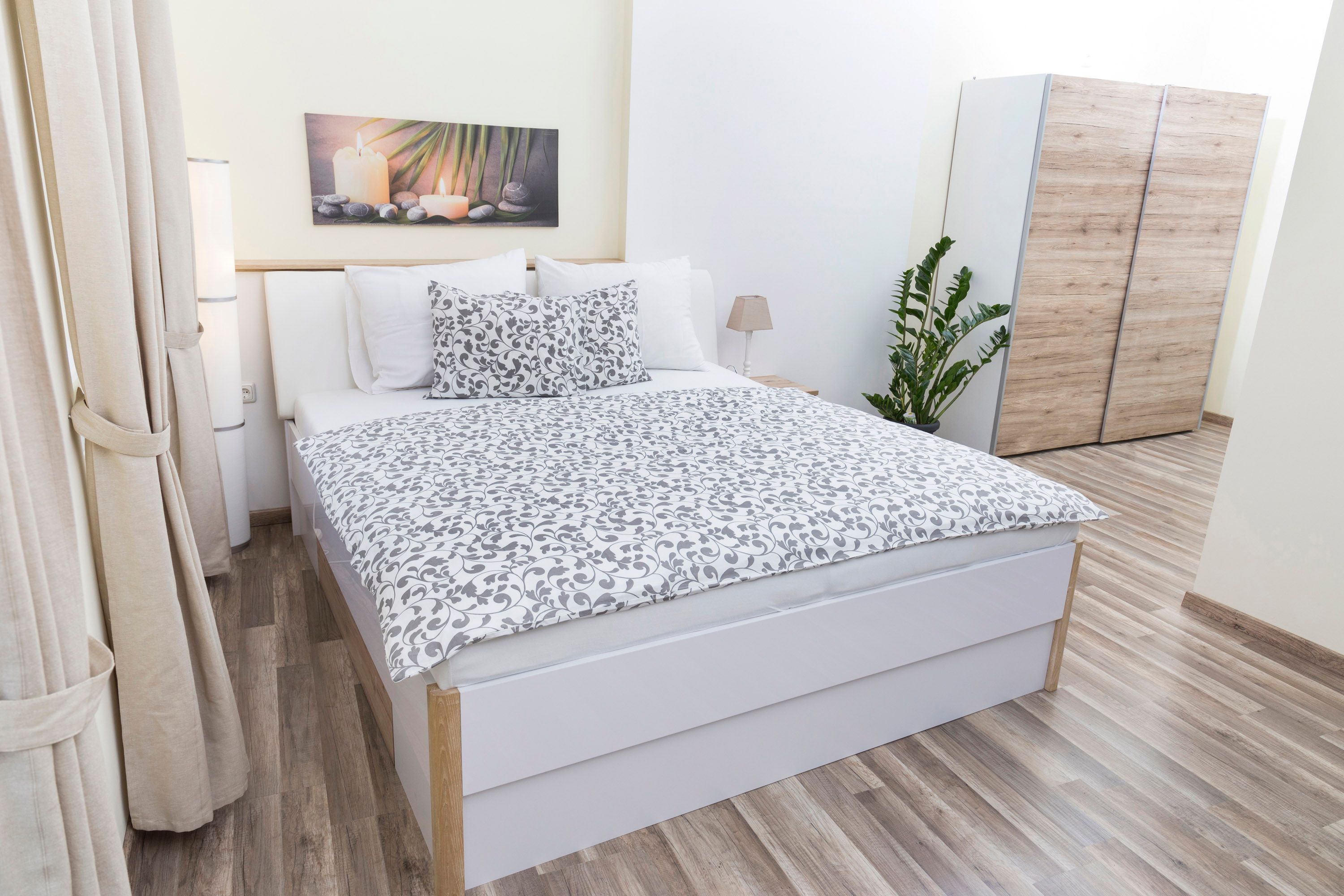 Moderní ložnice s manželskou postelí, rostlinami a šatní skříní.