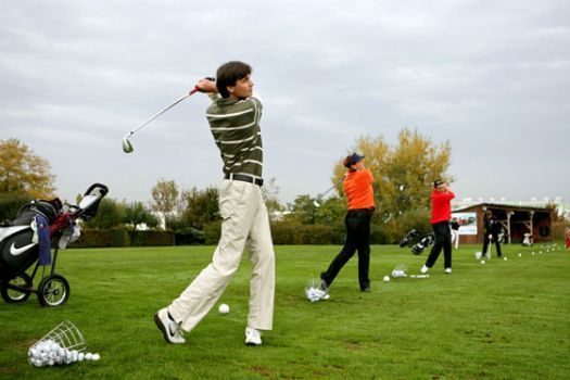 Lidé hrající golf na driving range.