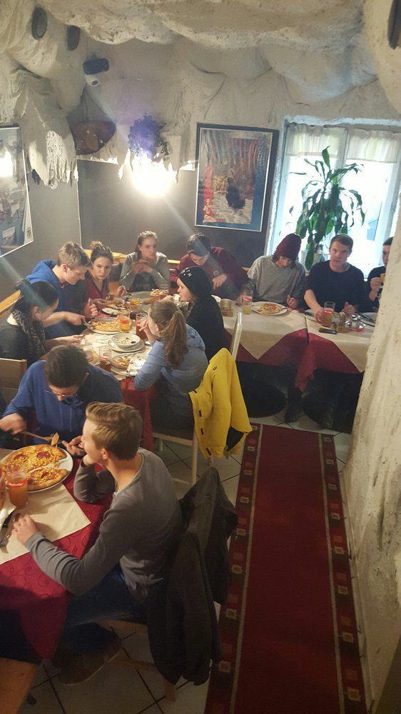 Skupina lidí jí pizzu v útulné restauraci s jeskynními stěnami.