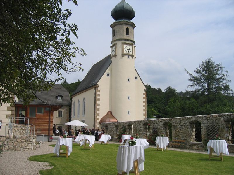 Kostel s věží a zahrada s barovými stoly, svatební scéna.