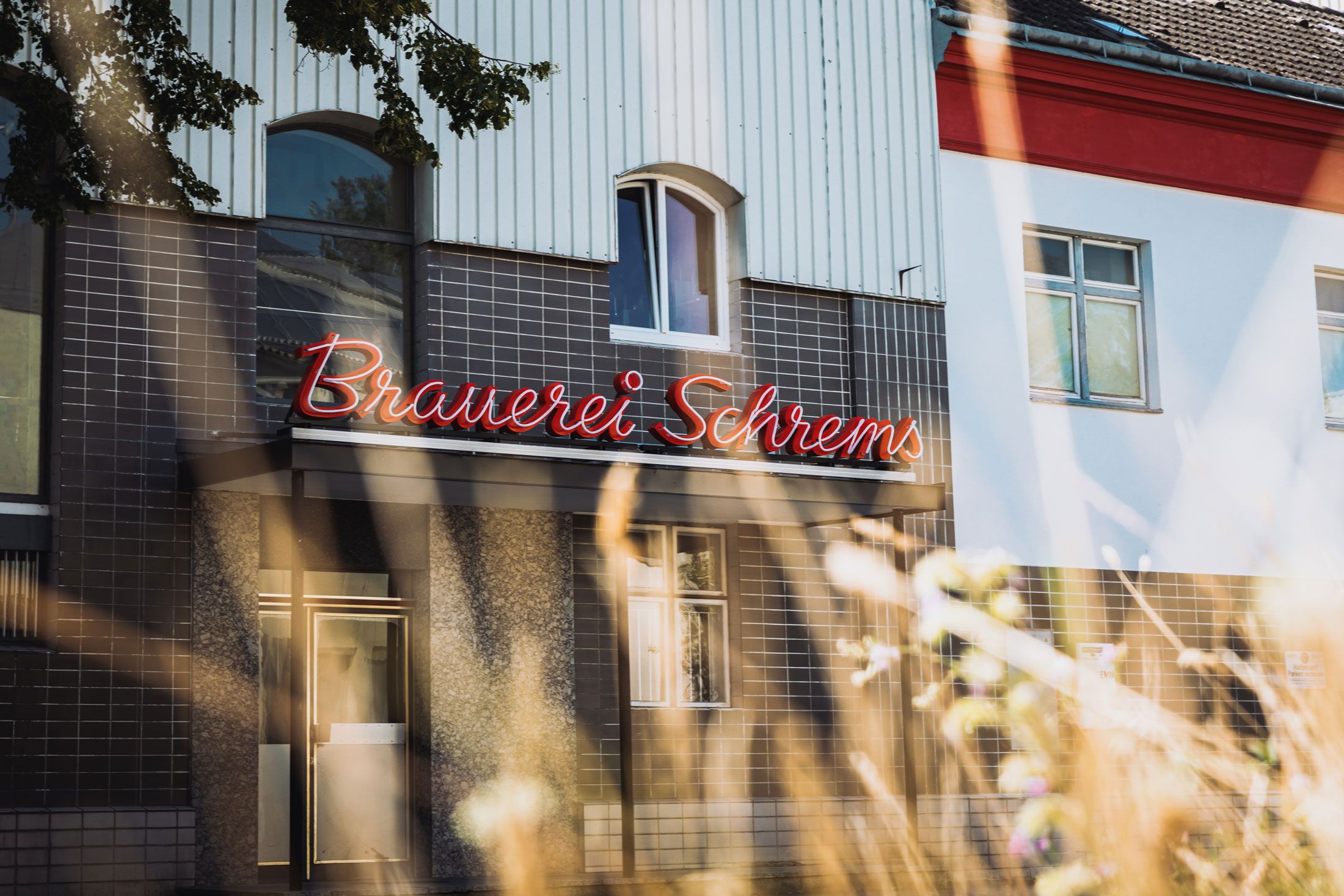 Fasáda pivovaru Schrems s červeným osvětleným nápisem.