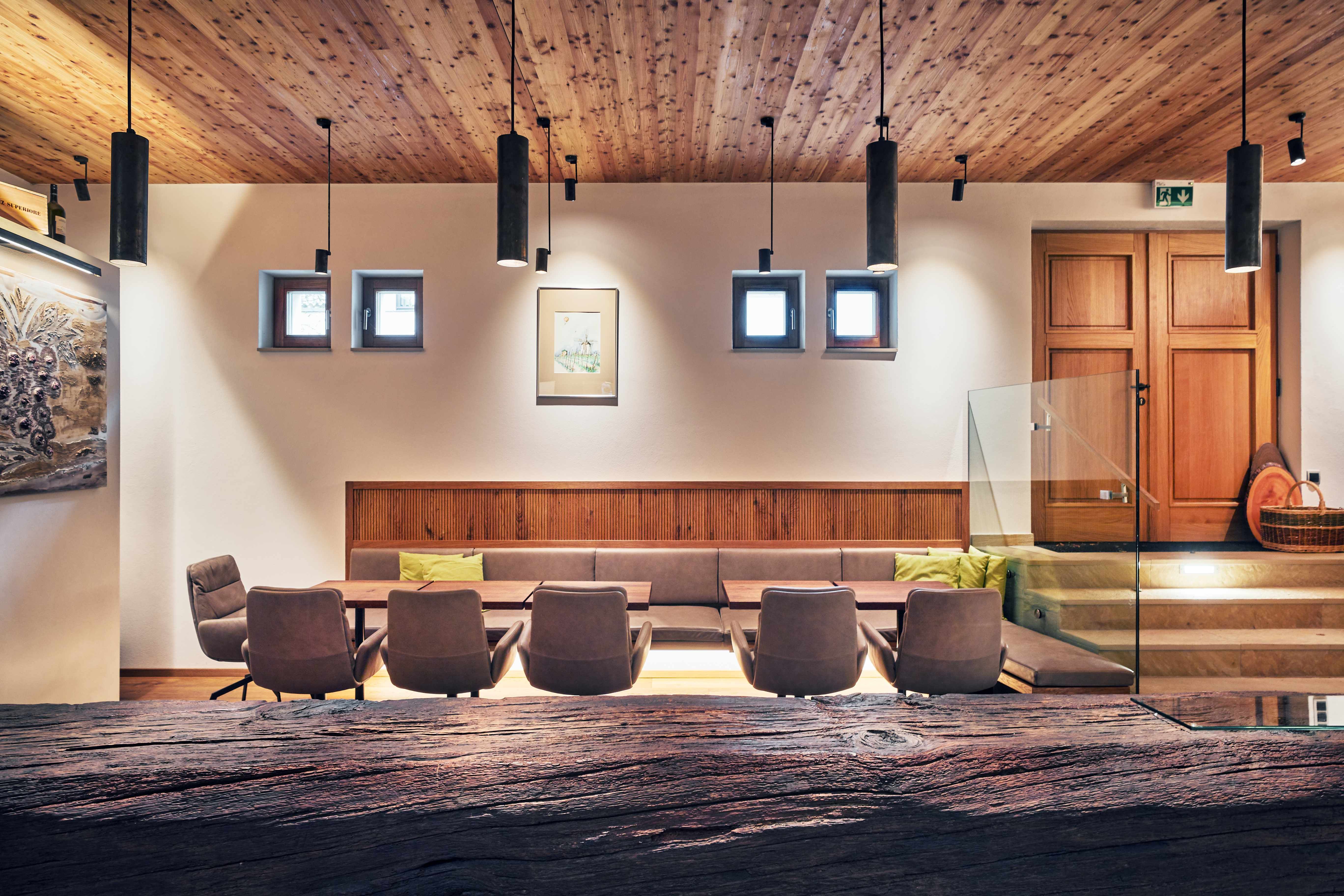 Moderní interiér s dřevěnými prvky, posezením a dekorativními lampami.