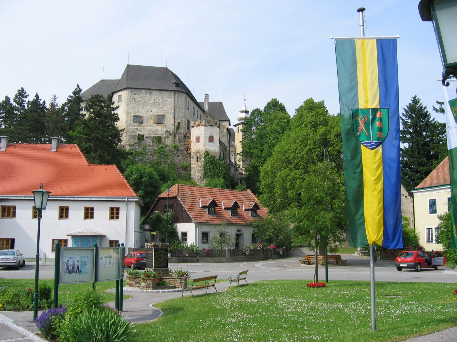 Hlavní náměstí v Albrechtsbergu se zámkem v pozadí a vlajkou v popředí.