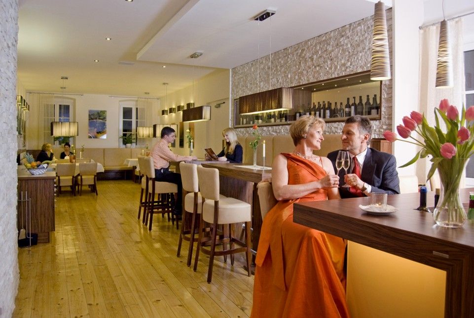 Elegantní restaurace se stoly pro páry a barem.