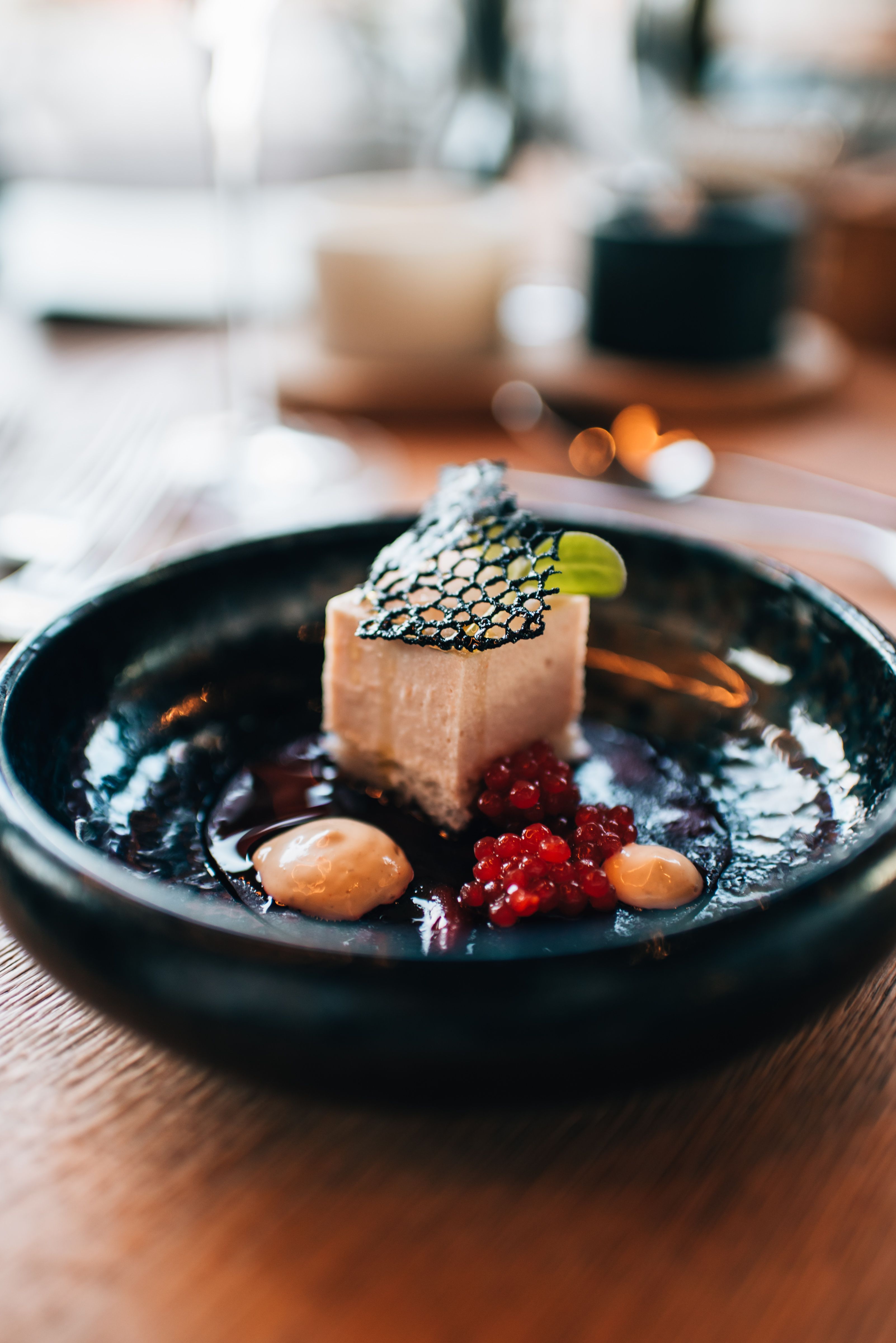 Moderní architektura vinařství za soumraku s osvětlenými interiéry a okolními budovami.