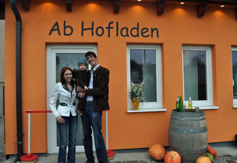 Rodina před farmářským obchodem Schäfer v Maria Ellend, vyzdobeným dýněmi a sudem na víno.