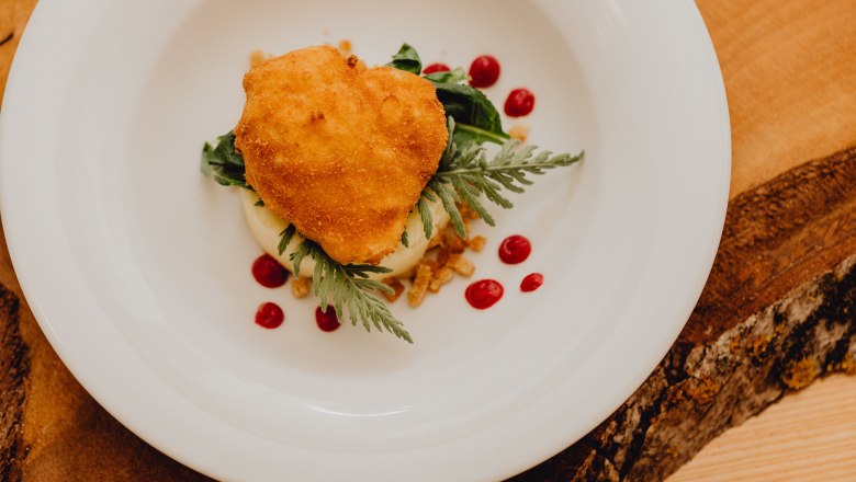 Pečené vejce na talíři s pyré a červenými puntíky.