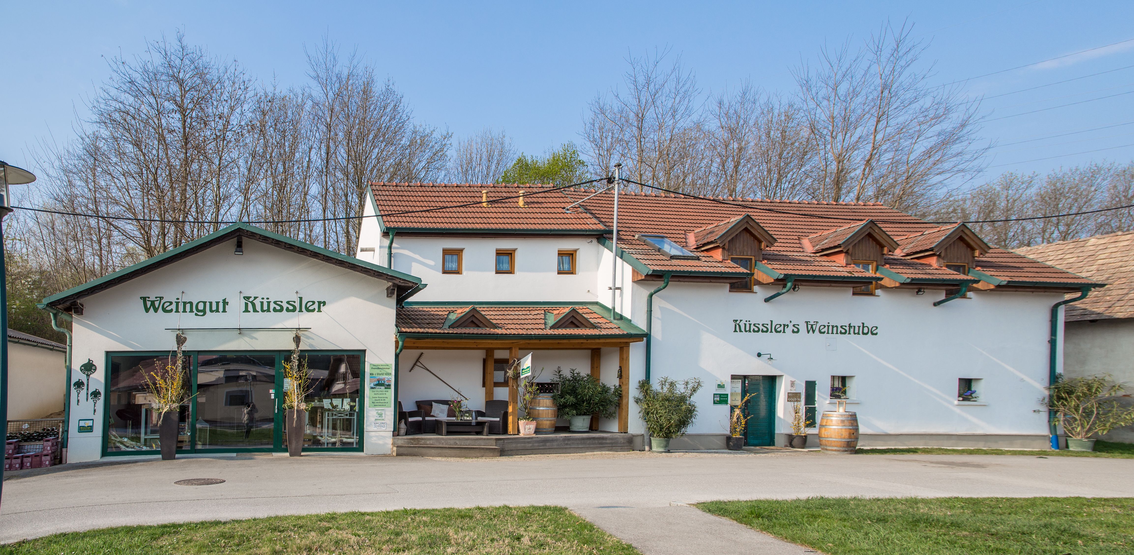 Vinařství Weingut Küssler s vinárnou a terasou, obklopené stromy.