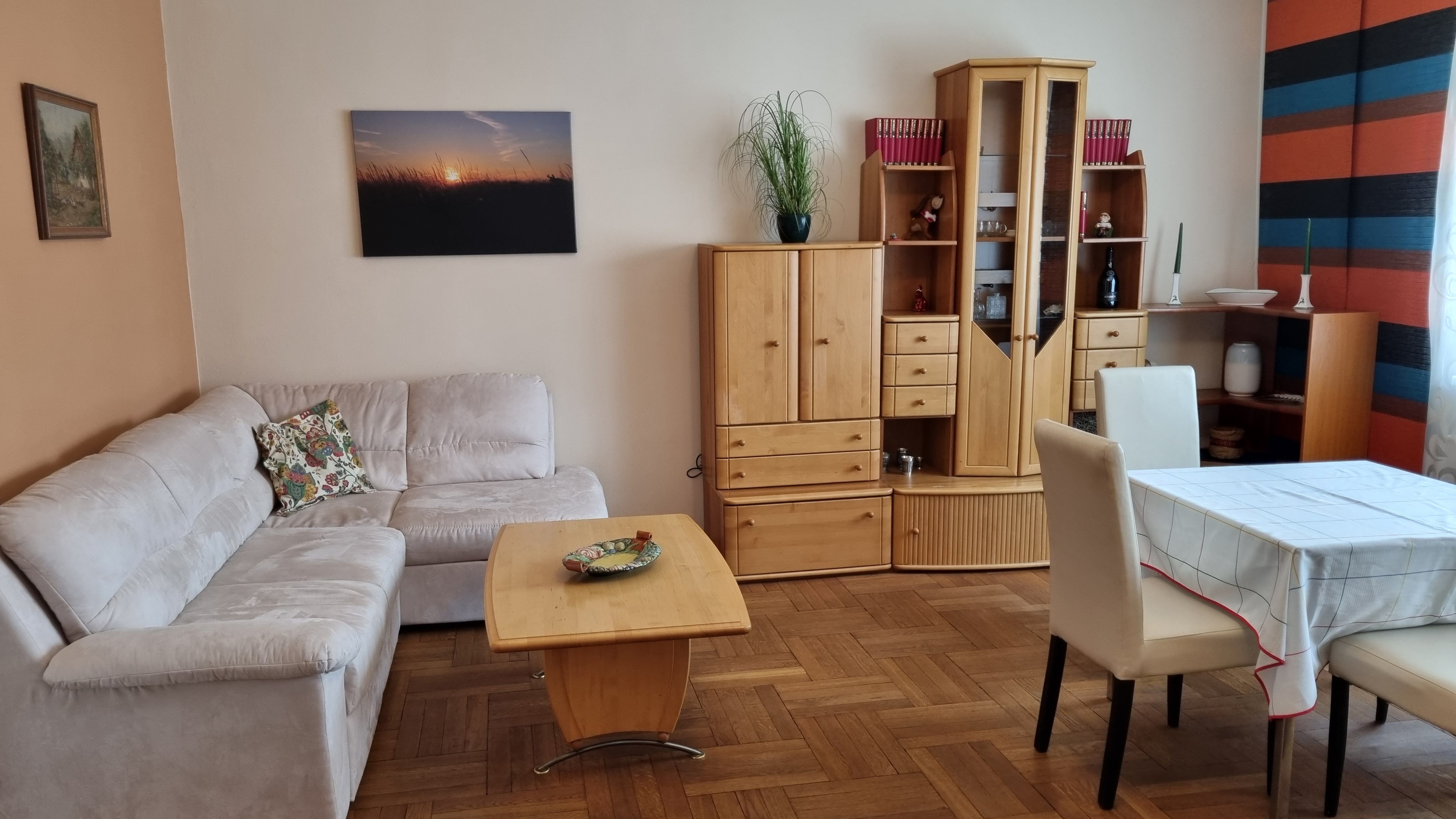 Obývací pokoj s béžovou pohovkou, dřevěným nábytkem a jídelním stolem.