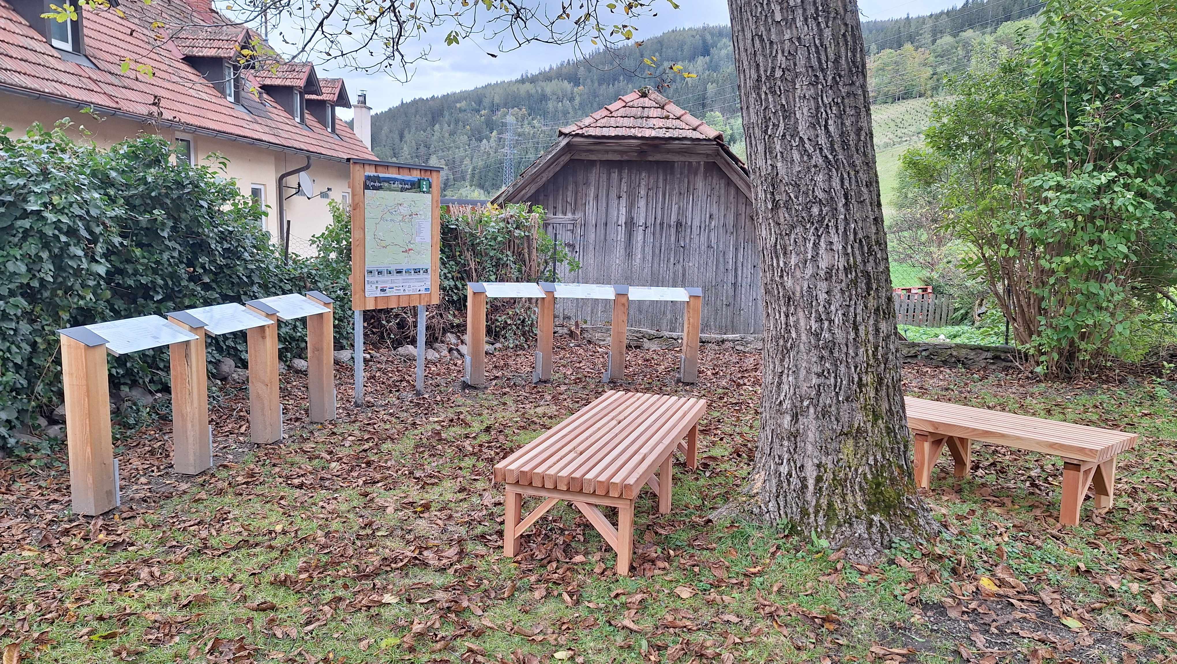 Dřevěné lavičky a informační tabule v zahradě Wittgensteinova domu.