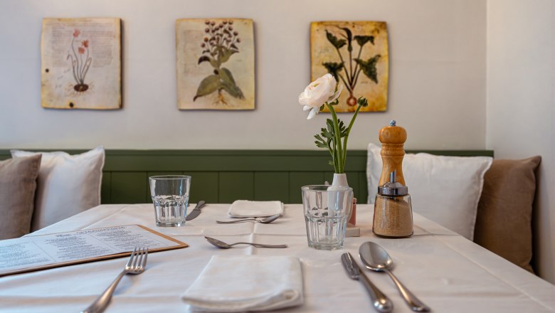 Stůl prostřen&yacute; v restauraci s květinami a kořen&iacute;m.