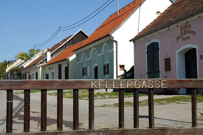 Historická sklepní ulička v Grafenwörthu s barevnými budovami a dřevěným plotem v popředí.