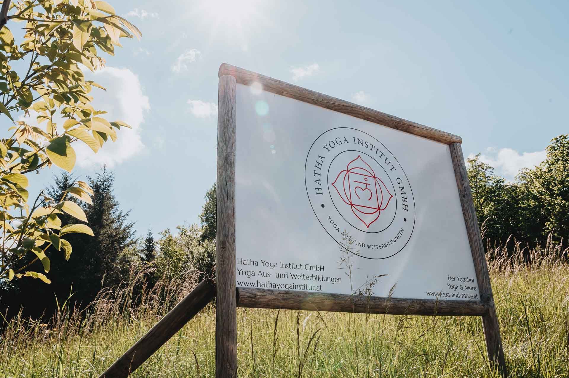 Na louce pod slunečnou oblohou stojí nápis Hatha Yoga Institute.