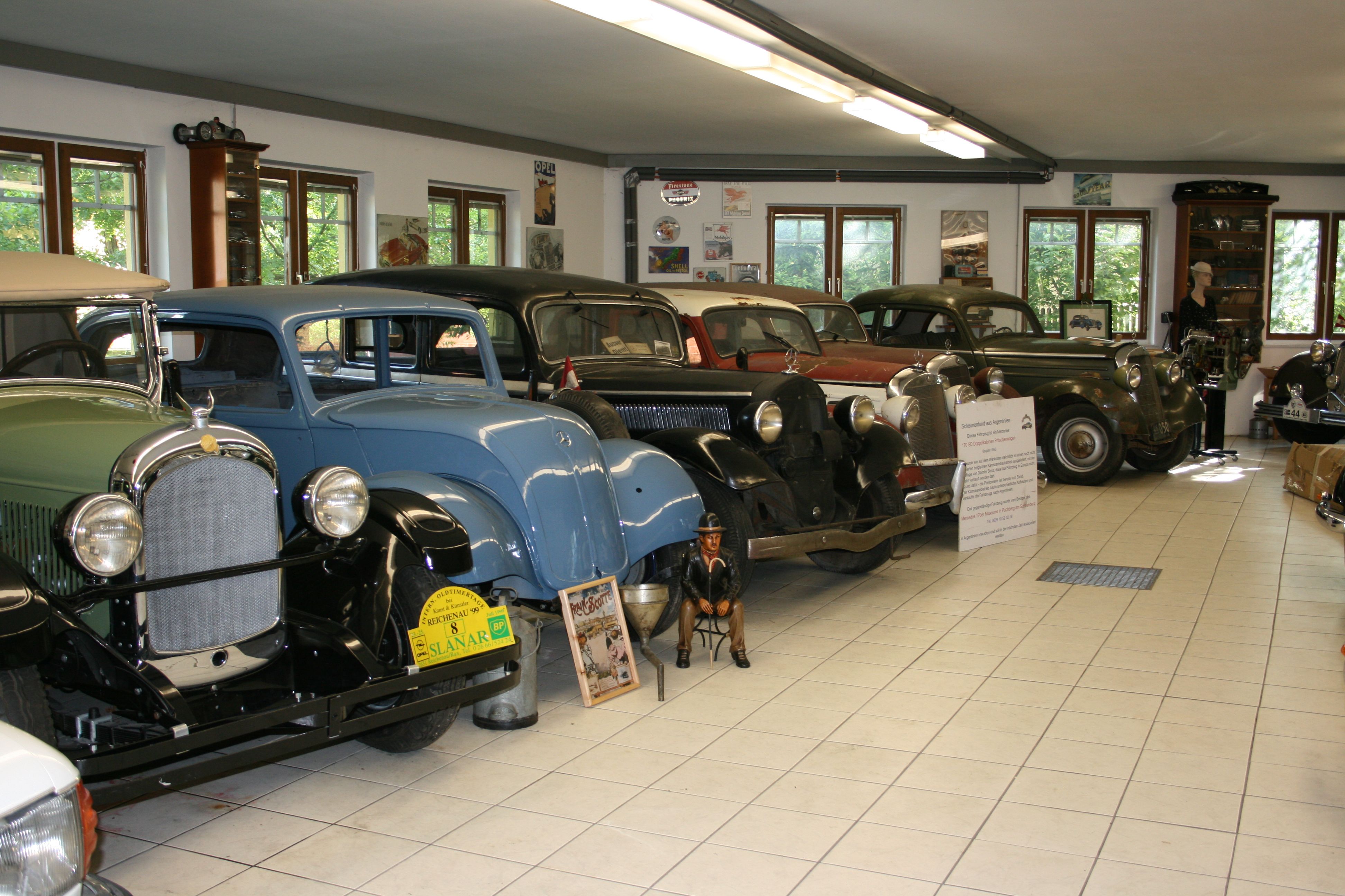 Pohled do interiéru muzea klasických automobilů s několika klasickými vozy v řadě.