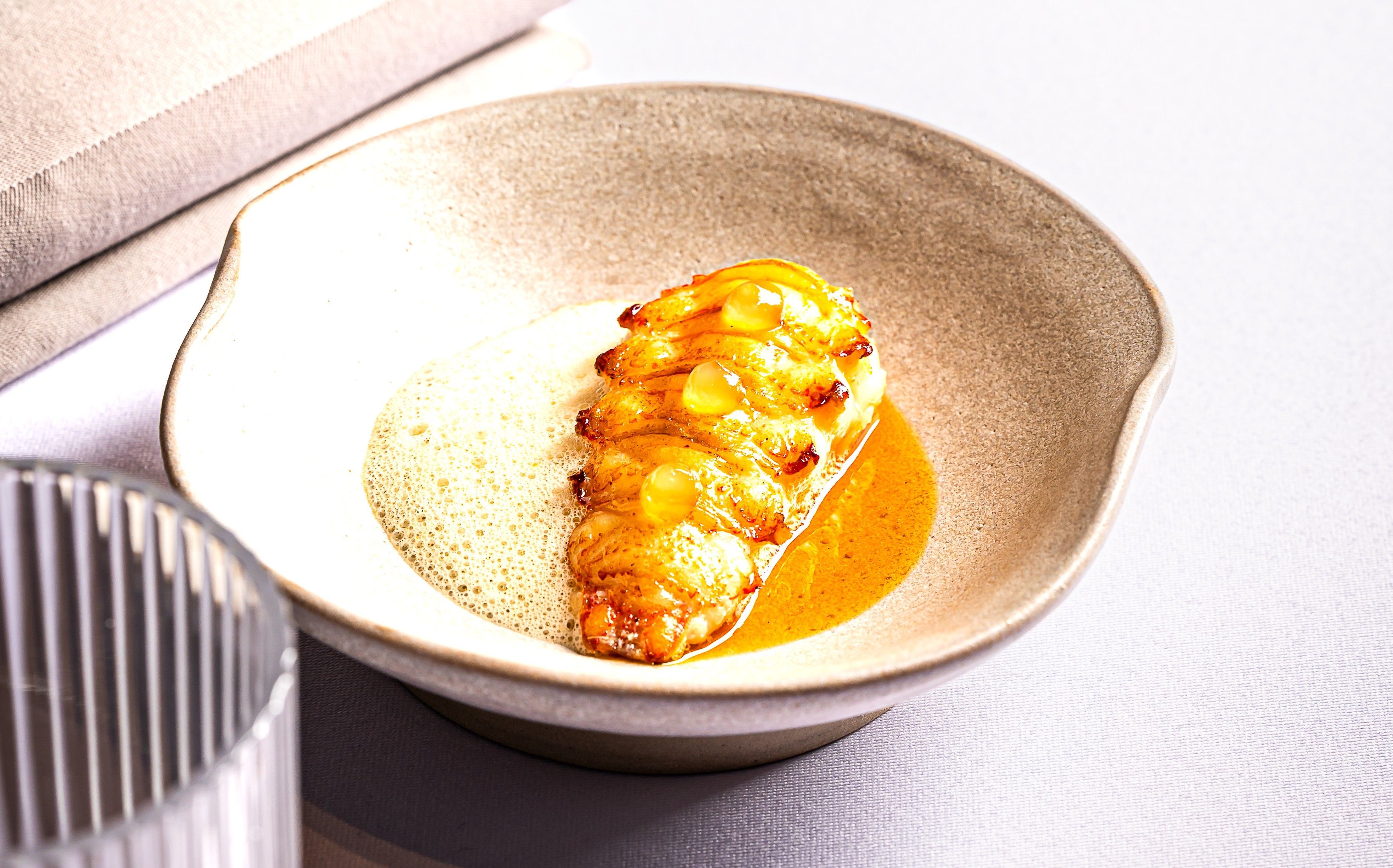 Uměle připravený pokrm v misce s pěnou a omáčkou.