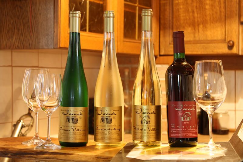 Čtyři láhve vína a sklenice na stole v kuchyni.