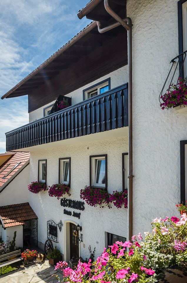 Tradiční penzion s květinami zdobeným balkonem a fasádou.