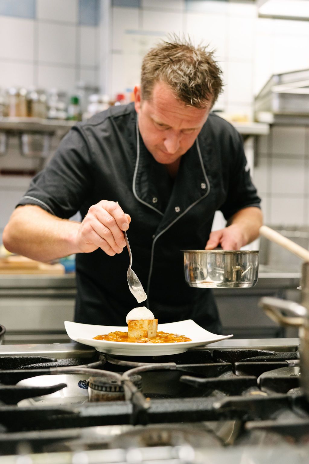 Kuchař zdobí pokrm v profesionální kuchyni.