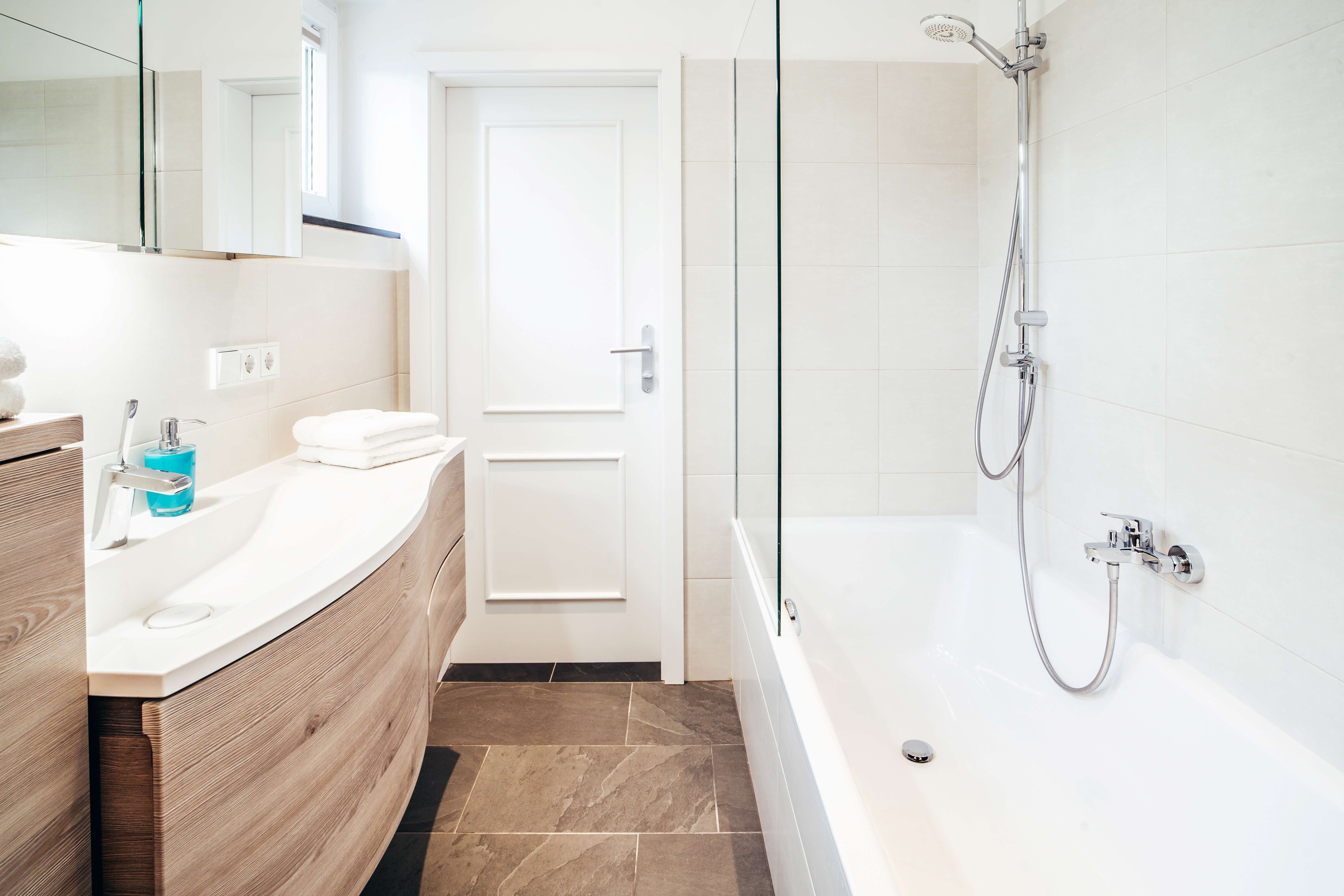 Moderní koupelna s vanou, umyvadlem a zrcadlem.