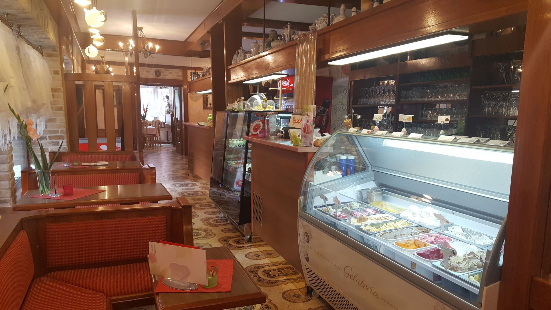 Pohled do interiéru kavárny se zmrzlinovým pultem a posezením.