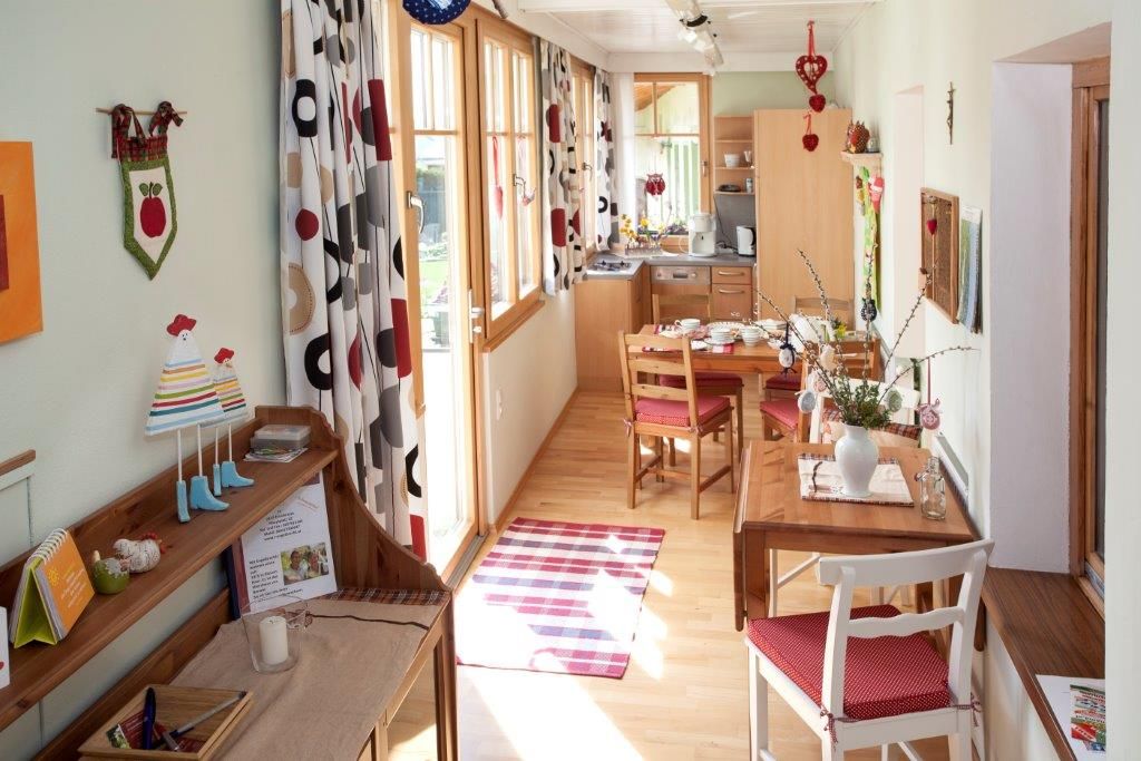 Útulný prázdninový byt s dřevěným nábytkem, jídelním stolem a dekorativními závěsy.