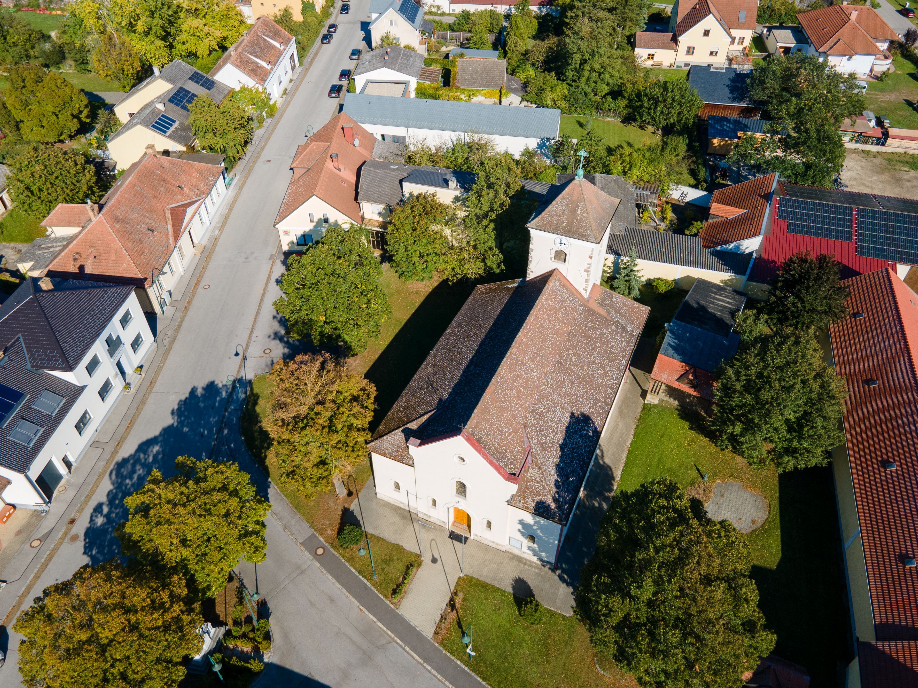 Letecký snímek obce Weiden an der March s kostelem, obytnými domy, ulicemi a spoustou zeleně.