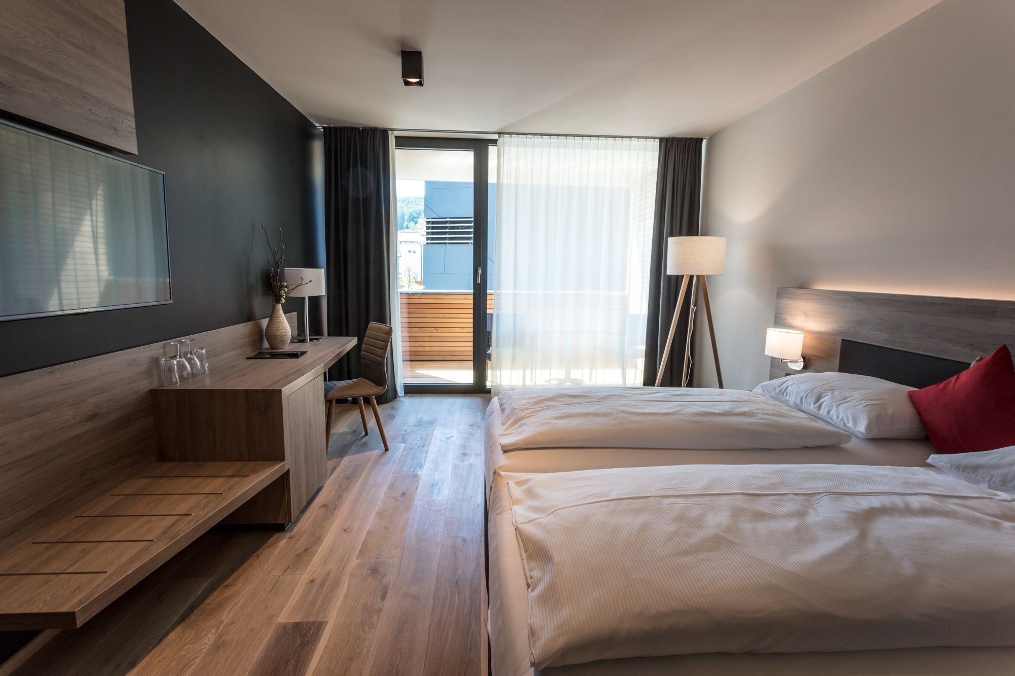 Moderní hotelový pokoj se dvěma lůžky, psacím stolem a balkonem.