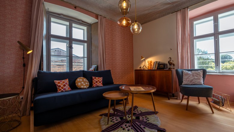 &Uacute;tuln&yacute; ob&yacute;vac&iacute; pokoj s pohovkou, křesly, kobercem a z&aacute;věsn&yacute;mi lampami.