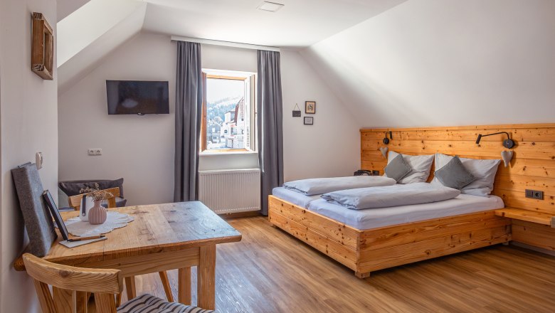 Bytový dům Leopold an der Ybbs, © Niederösterreich Werbung / Maximilian Pawlikowsky Útulná ložnice s dřevěným nábytkem a šikmým stropem.