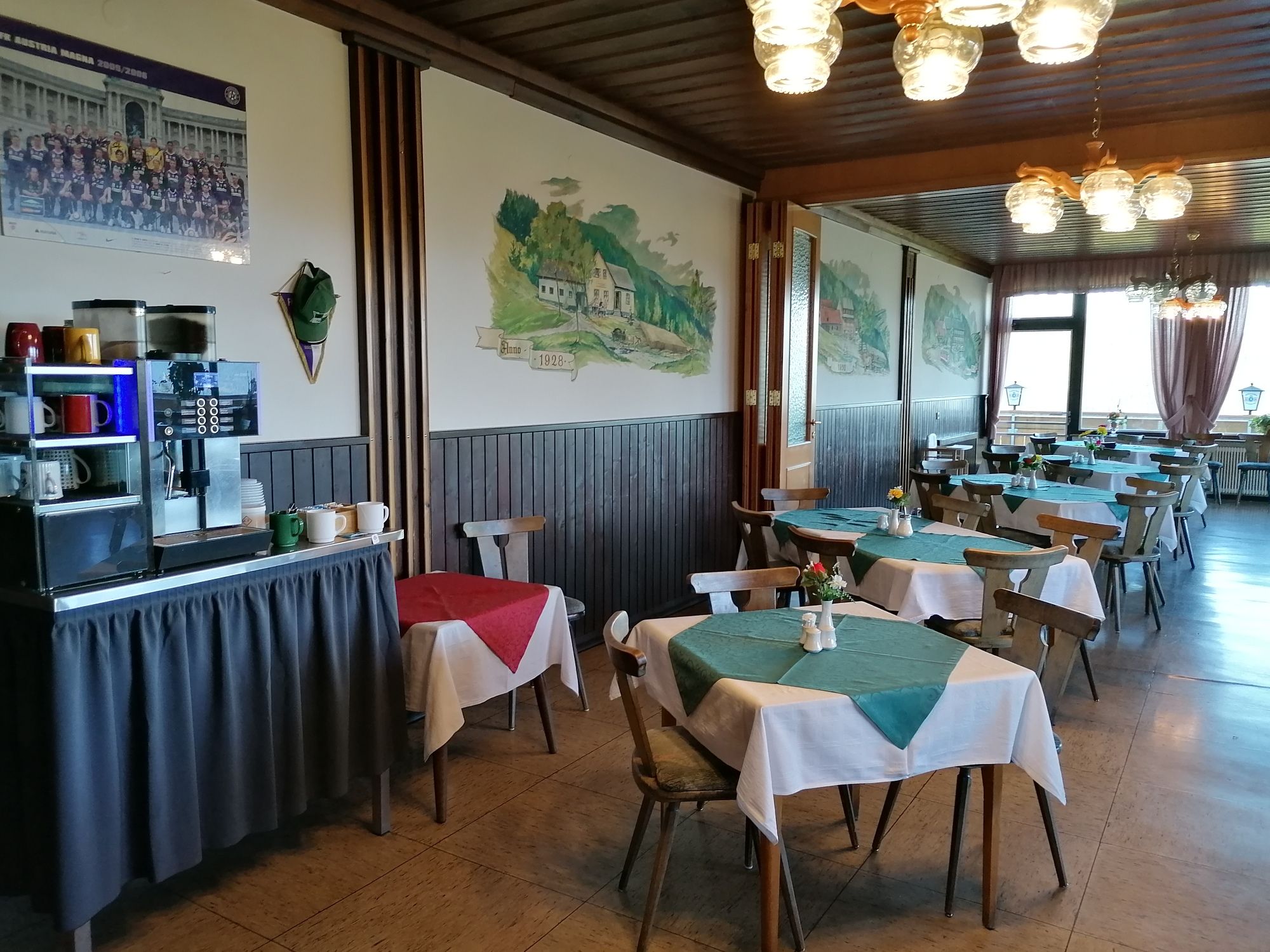 Pohled do interiéru restaurace s dřevěným nábytkem a ubrusy.