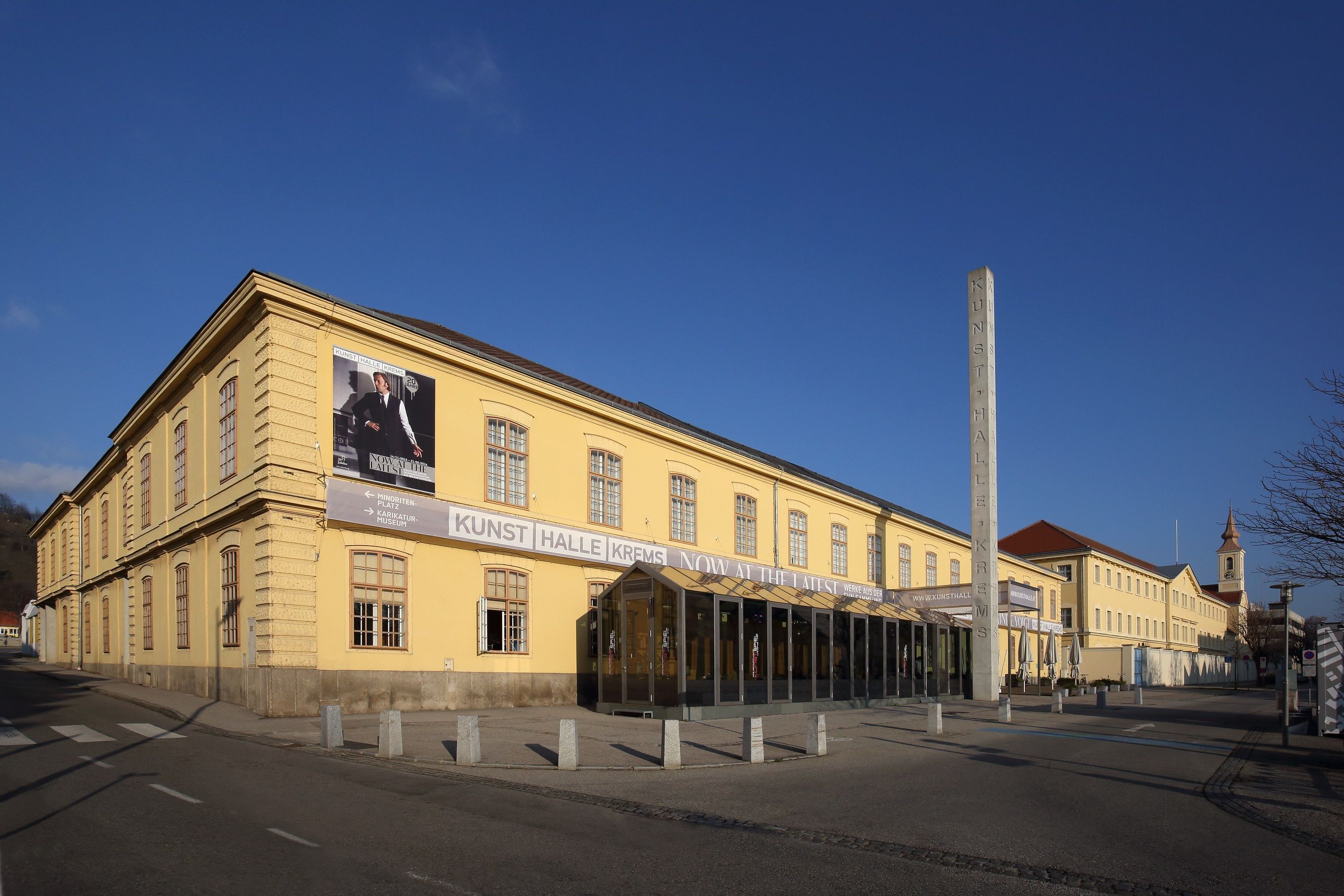 Pohled zvenčí na Kunsthalle Krems se žlutou budovou a modrou oblohou.