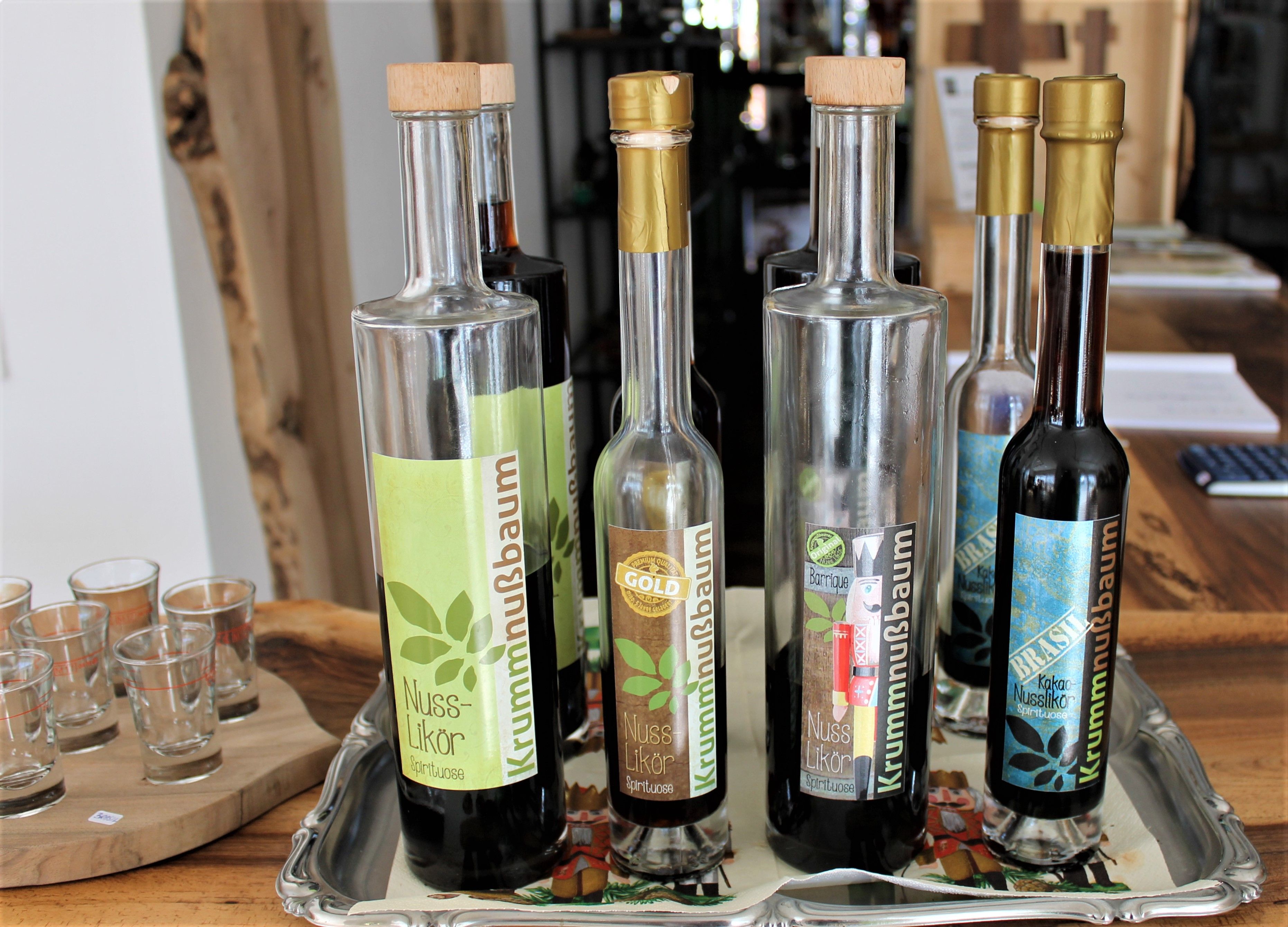 Několik lahví ořechového likéru na tácku a vedle nich skleničky.