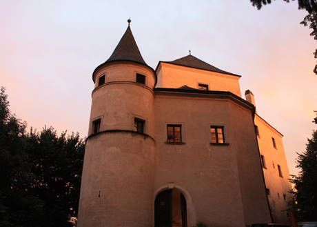 Hrad Wildegg při západu slunce s osvětlenými věžemi a okny.