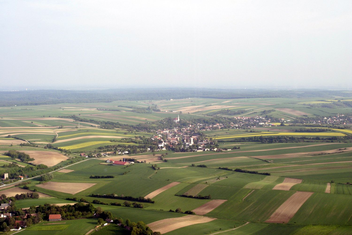 Letecký pohled na Hochleithen, obklopený poli a lesy.
