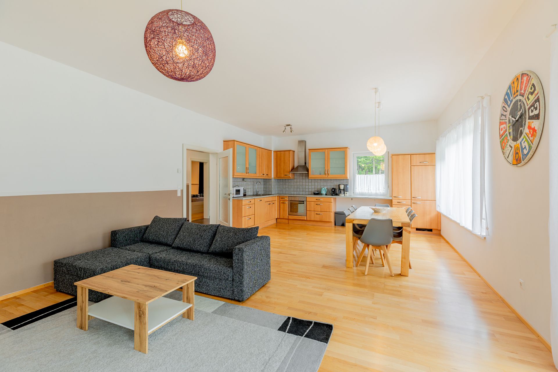 Otevřený obývací prostor s kuchyní, jídelním stolem a pohovkou.