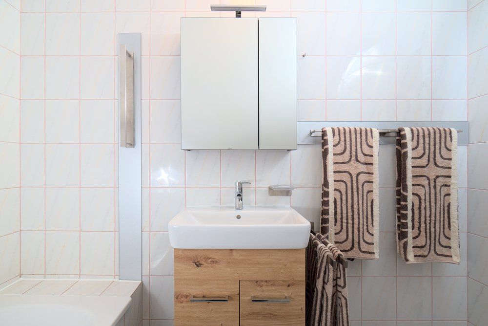 Moderní koupelna s umyvadlem, zrcadlem a ručníky.