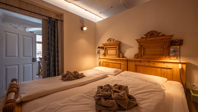 &Uacute;tuln&aacute; ložnice se dvěma samostatn&yacute;mi lůžky a dřevěn&yacute;mi dekoracemi, př&iacute;jemně osvětlen&aacute;.