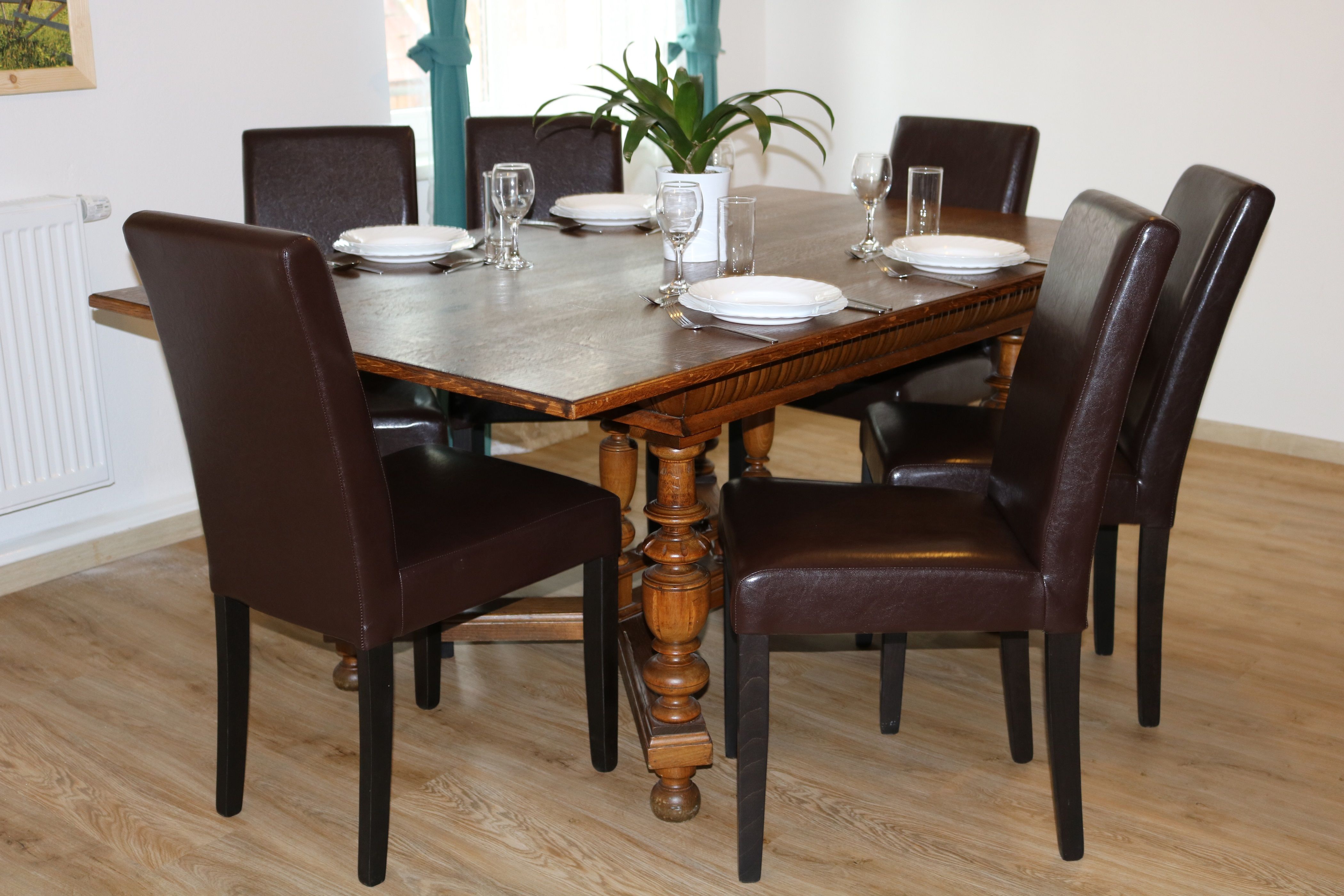 Jídelní kout s dřevěným stolem a šesti hnědými židlemi pro šest osob.