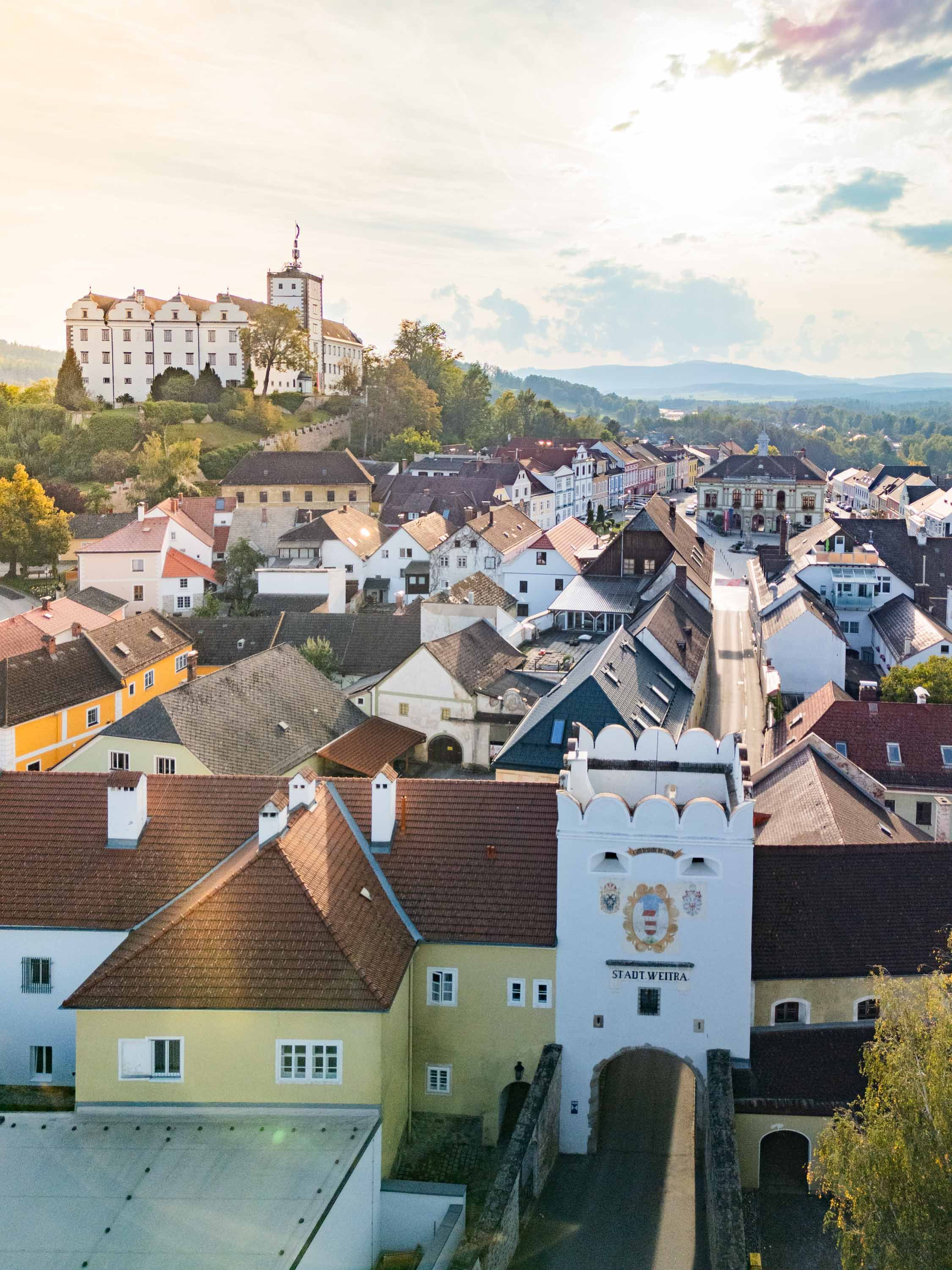 Letecký pohled na historické centrum města Weitra s hradem a městskou branou v popředí.