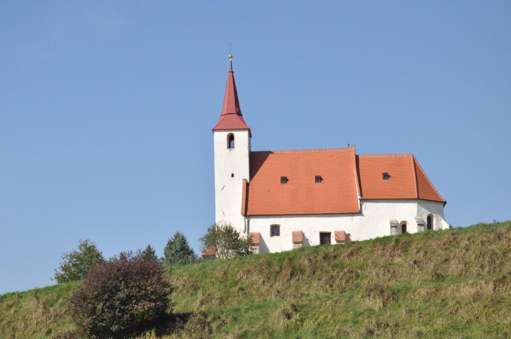 Farní kostel v Ofenbachu na kopci s modrou oblohou v pozadí.