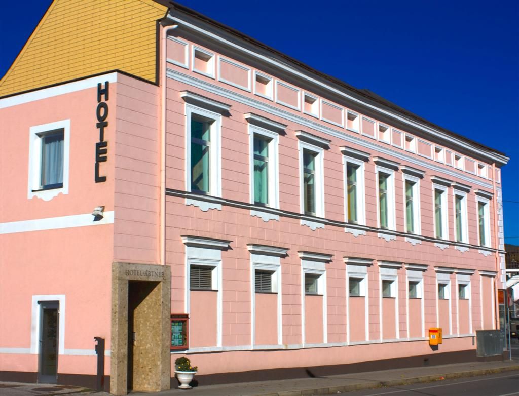 Růžová budova s nápisem "Hotel" na fasádě.