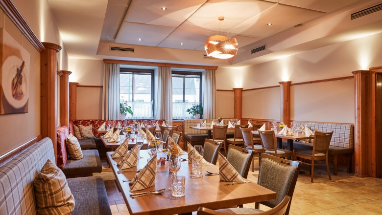 Útulná jídelna s prostřenými stoly a dřevěným obložením.