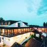 Moderní architektura vinařství za soumraku s osvětlenými interiéry a okolními budovami.