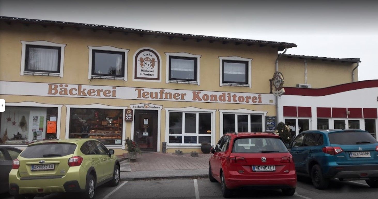 Pohled na pekárnu Teufner zvenčí a zaparkovaná auta před ní.