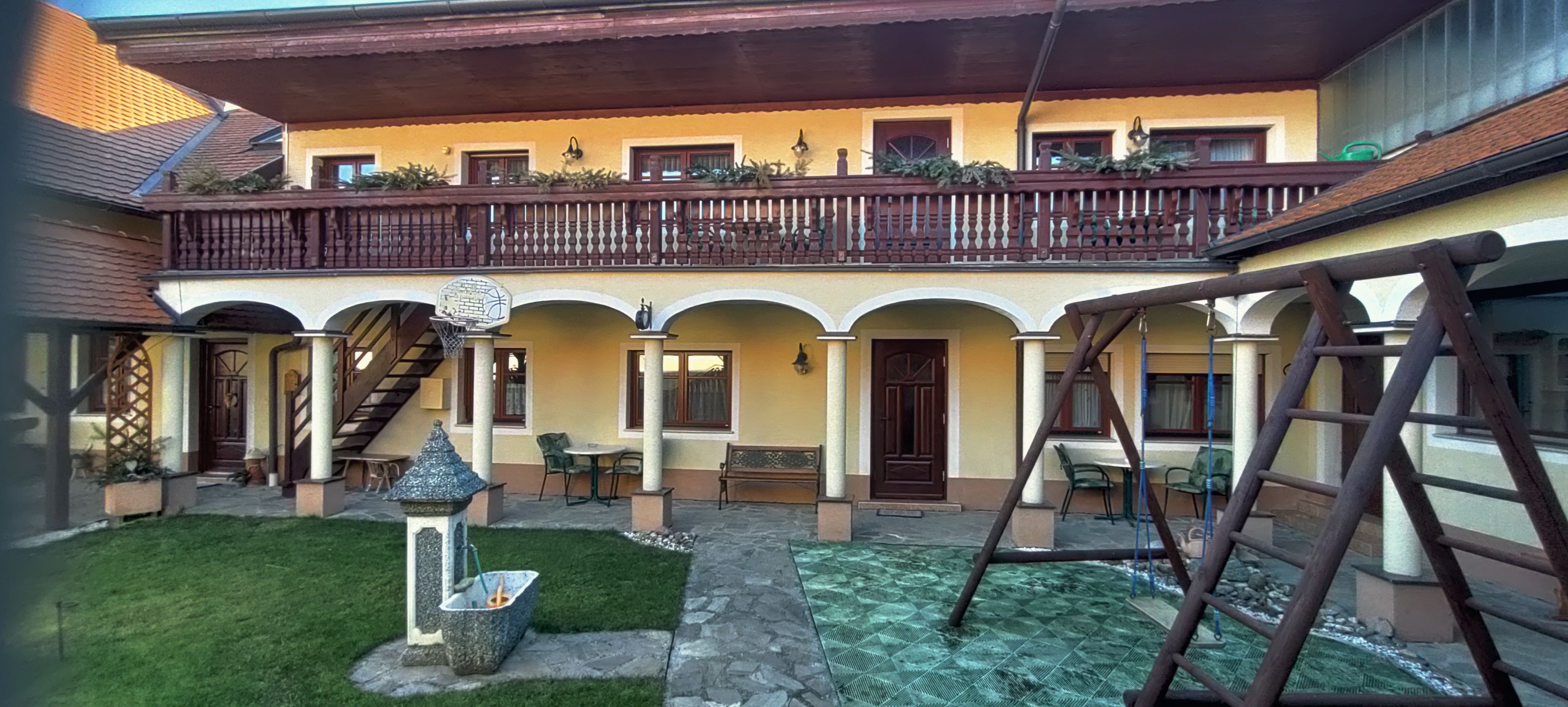 Vnitřní dvůr s arkádami, balkonem, houpačkou a fontánou.