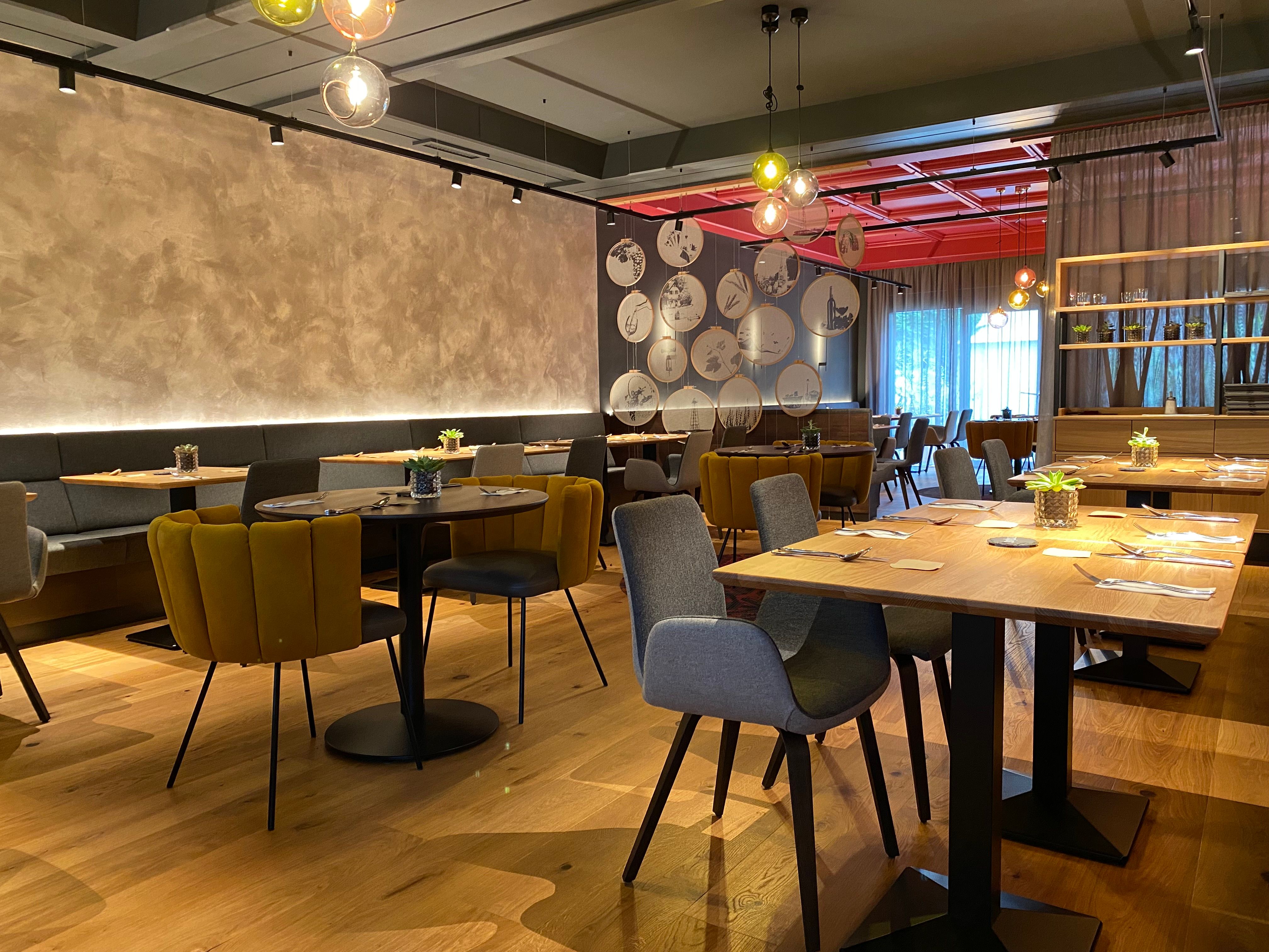 Moderní restaurace se stylovým nábytkem, dřevěnými stoly a útulnými židlemi.