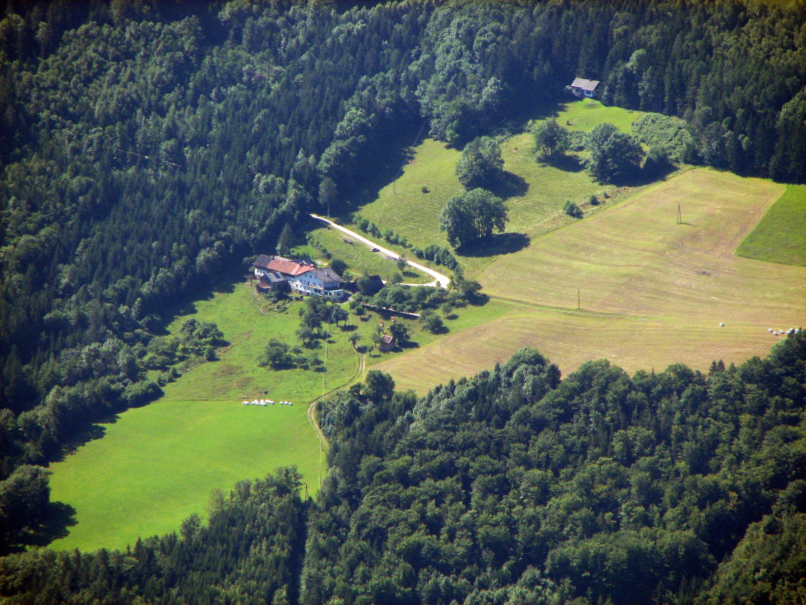 Letecký pohled na farmu obklopenou lesy a loukami.