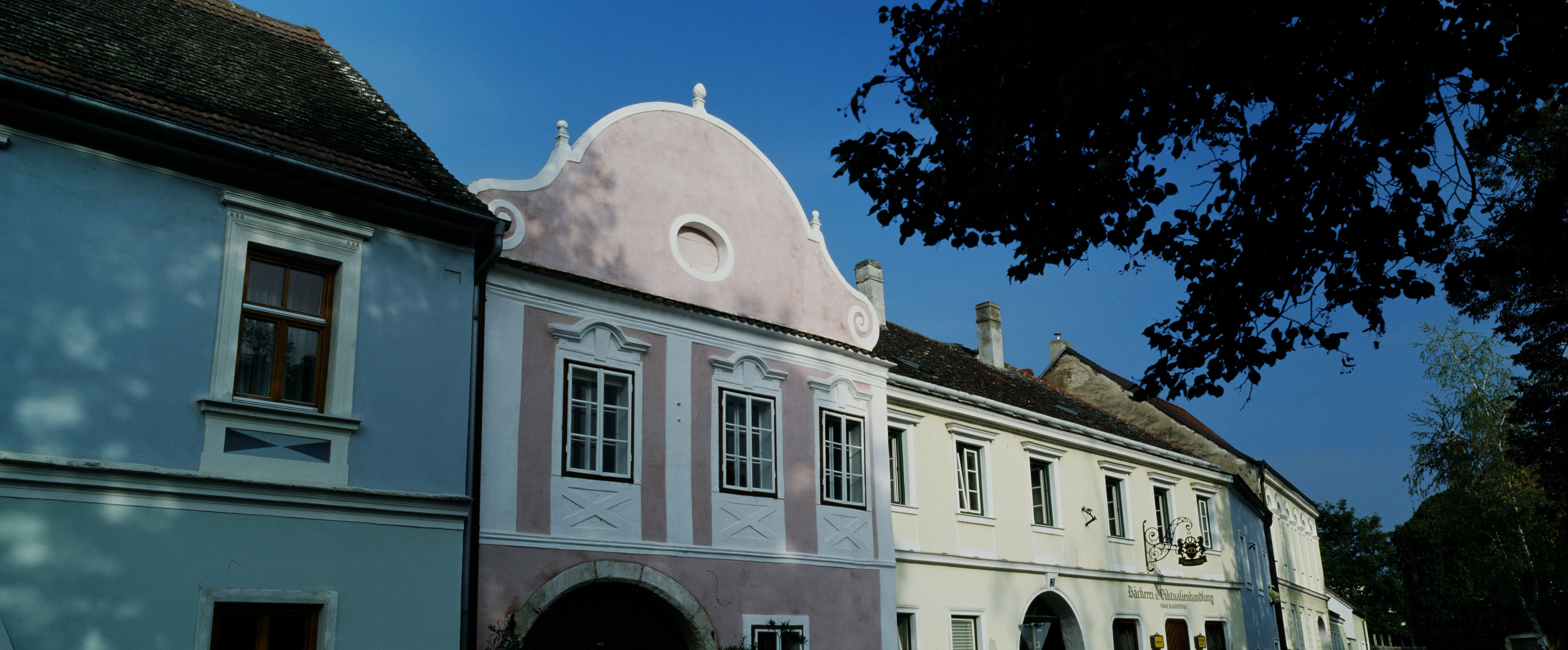 Historické budovy v Hadersdorfu-Kammernu s modrými a růžovými fasádami.